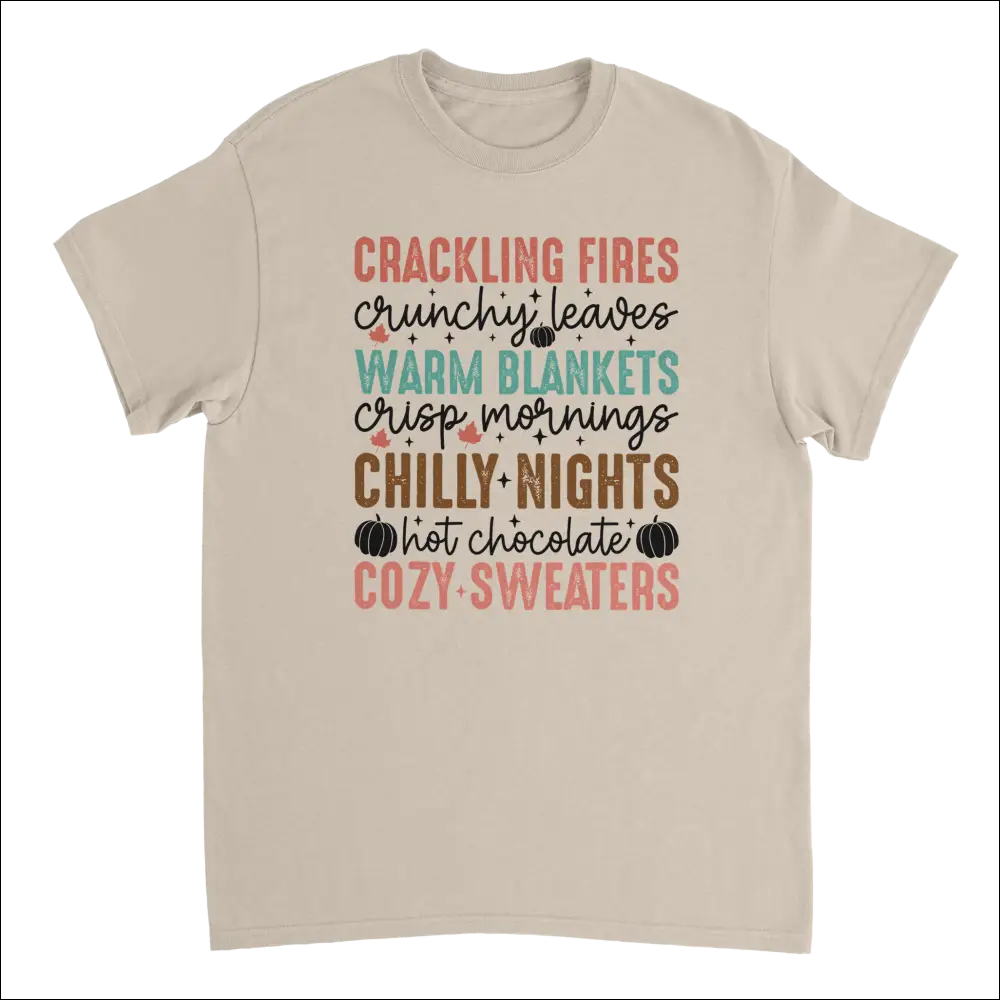 Beige short-sleeved Autumn Comforts T-shirt with colorful graphic print of crackling fires, crunchy leaves, and cozy sweaters