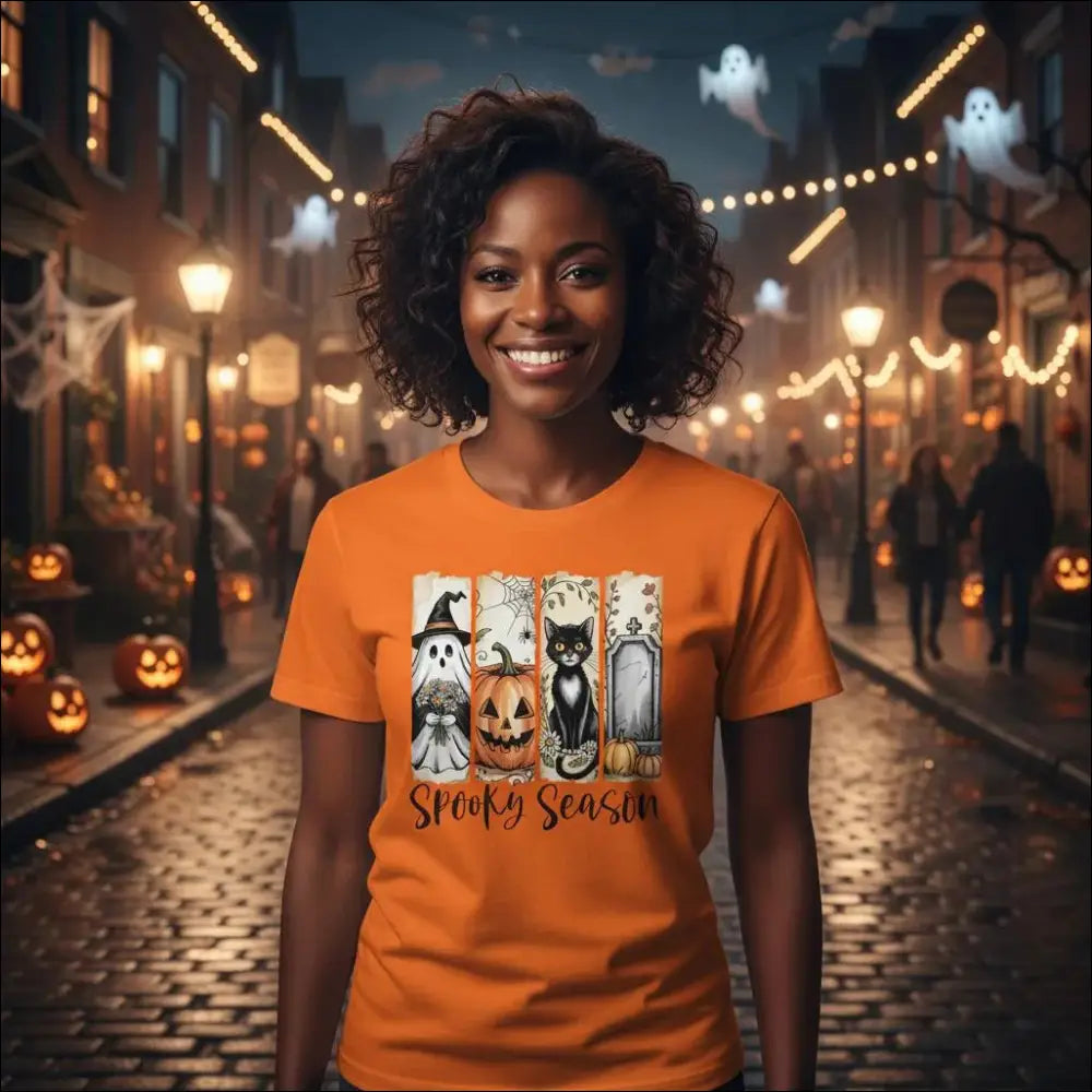 Orange short-sleeved Halloween t-shirt with spooky ghosts, pumpkins, cats, tombstones and Spooky Season text in Autumn Spooks Cotton Tee design